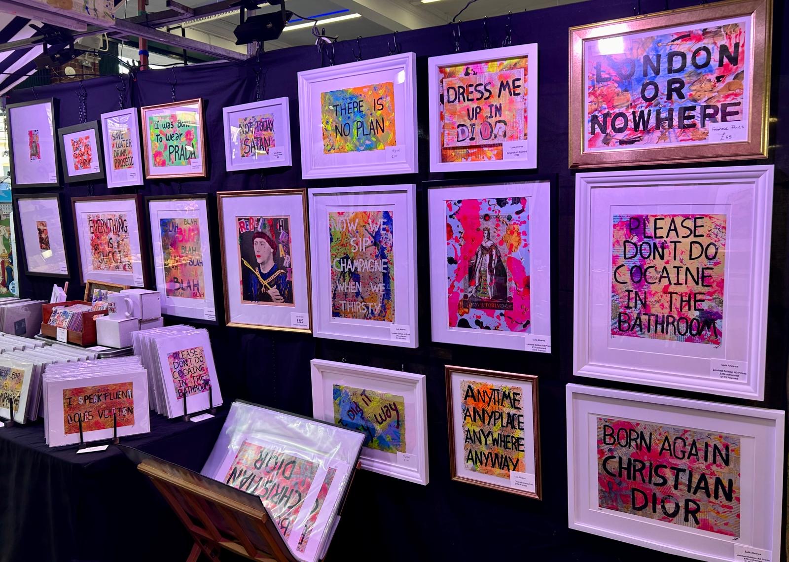 The wall of framed prints and originals at Luis's stall